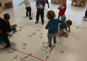 Zdjęcie dzieci zbierających z podłogi papierowe śnieżki.