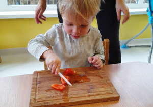 Chłopiec kroi pomidora.