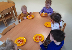Maluchy przy wspólnym stole podczas konsumowania pizz.