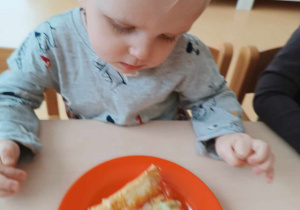 Tobiasz przygląda się swojemu kawałkowi pizzy.
