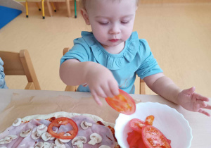 Aleksandra wyciąga z białej miseczki plasterek pomidora.