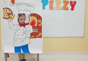 Dziewczynka pozuje do zdjęcia na ściance z okazji Dnia Pizzy.