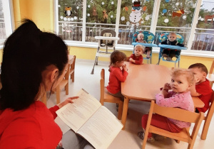 Opiekunka czyta wiersz dzieciom.
