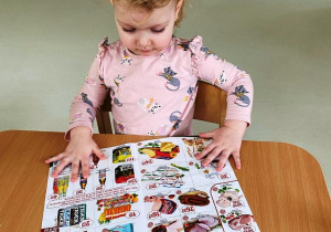 Zdjęcie dziewczynki przegladającej broszurę.