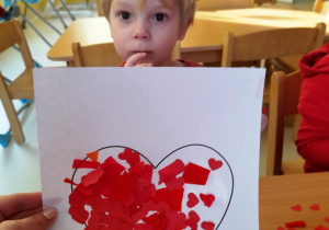 Zdjęcie chłopca z wykonanym sercem z bibuły.