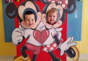 Chłopiec i dziewczynka ustawieni do wspólnego zdjęcia na sciance z Myszką Mickey i Minnie.
