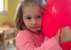 Dziewczynka przytulajaca serduszkowego balona.