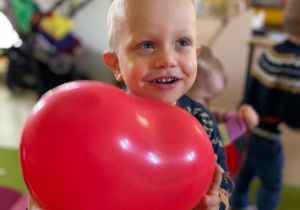 Uśmiechnięty chłopiec z czerwonym balonem.