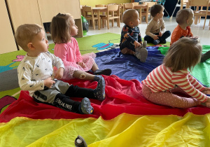 Dzieci z grupy Żabki siedzące na kolorowej chuście.