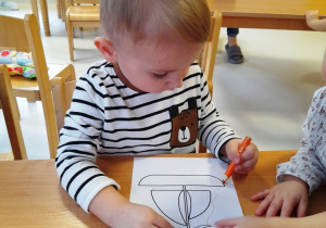 Chłopiec maluje szablon żaglówki.