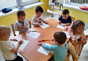Dzieci siedzące przy stole w czasie kolorowania obrazków.