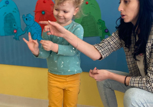 Dziewczynka demonstruje niebieskiego dinozaura z papieru.