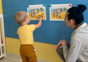 Mały chłopiec pokzuje palcem żółwia na obrazku.