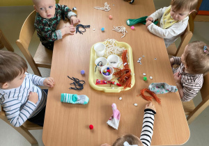 Dzieci z grupy Żabki siedzące przy stole podczas wykonywania skarpetkowych pacynek.