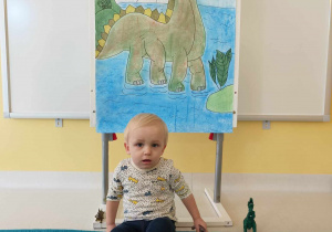 Tobiasz pozuje do zdjęcia z zabawkowymi dinozaurami.