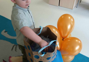 Zdjęcie Szymona wybierającego z urodzinowej torby pierwszy upominek dla dzieci z grupy.
