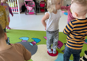 Dzieci stojące na kolorowych kołach z filcu w czasie zajęć.