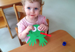 Dziewczynka pozuje ze swoją zieloną żabką.