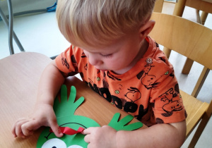 Chłopczyk przykleja papierowy język do żabki.