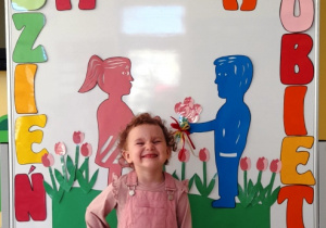 Uśmiechnięta dziewczynka pozująca na tle kolorowej ścianki.