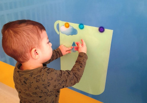 Chłopiec przykleja kropelkę z papieru do szablonu wielkiego garnka.