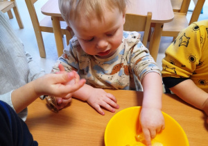 Chłopczyk dotyka kostki lodu.