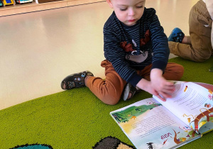 Chłopczyk obraca strony w kolorowej książce.