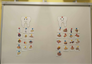 Zdjęcie tablicy z posegregowanymi przez dziećmi obrazkami ze zdrową i niezdrową żywnością.