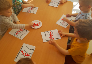 Dzieci z grupy Biedroneczki podczas pracy plastycznej z okazji Dnia Flagi.