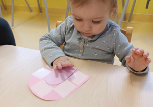 Karina przykleja na szablon papierowej buzi, język wycięty z różowej pianki.
