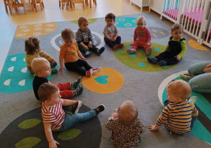 Zdjęcie dzieci z grupy Motylki siedzących na dywanie, przygotowujących się do zajęć z okazji Dnia Logopedy.