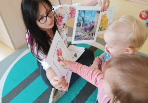 Opiekunka pokazuje Laurze i Kornelii wydrukowane obrazki tulipanów i wiosennych krokusów.