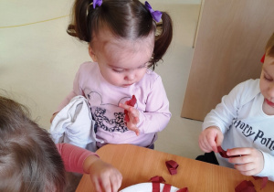 Dzieci naklejają kawałki brązowej bibuły na papierowy talerz.