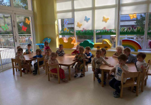 Zdjęcie dzieci z grupy Pszczółki siedzących przy stoliczkach i przygotowujących się do zajęć plastycznych pt. ,,KWITNĄCE DRZEWKA''.