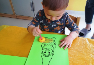 Chłopiec stempluje swojego krasnala za pomocą żółtej farby.