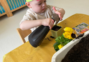 Chłopiec podlewający swoją roślinkę.