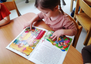 Dziewczynka przegląda książkę.