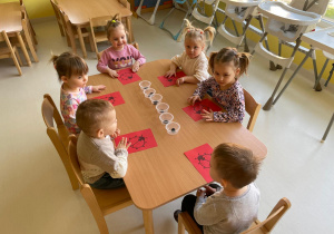 Dzieci z grupy Żabki przy wspólnym stole podczas pracy plastycznej.
