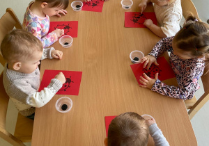 Dzieci przy stoliku robią prace plastyczne.