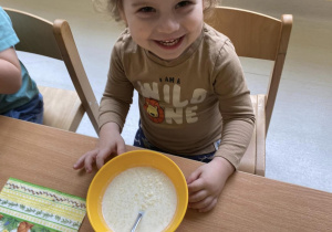 Szymon pozuje do zdjęcia podczas jedzenia zupki mlecznej.