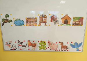Zdjęcie tablicy suchościeralnej z zawieszonymi przez opiekunki wydrukowanymi obrazkami zwierząt i ich domków.