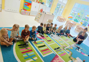 Zdjęcie dzieci z grupy Pszczółki siedzących na dywanie, przygotowujących się do zajęć pt. ,,POZNAJEMY WIEJSKIE ZWIERZĄTKA.''