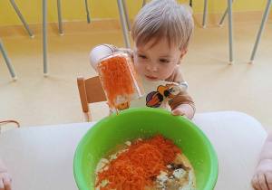 Stanisław wysypuje ze szklanki do plastikowej miski startą marchewkę.