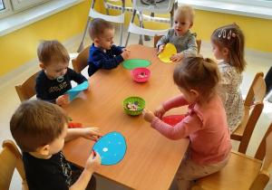 Dzieci przy wspólnym stole podczas wykonywania pracy plastycznej.