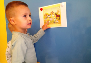 Zdjęcie chłopca pokazującego kury na obrazku.