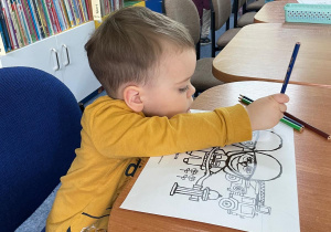 Chłopczyk maluje obrazek z Kicią Kocią.