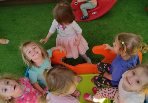 Zdjęcie uśmiechniętych dzieci podczas zabawy na tarasie.