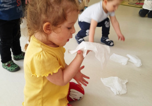 Dzieci próbujące zdmuchnąć chusteczki higieniczne z dłoni.