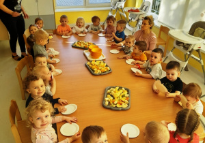 Dzieci siedzące przy wspólnym stole przed rozpoczęciem zajęć kulinarnych.
