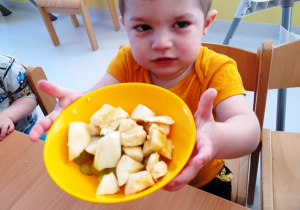 Chłopiec prezentuje swoją sałatkę z owoców.